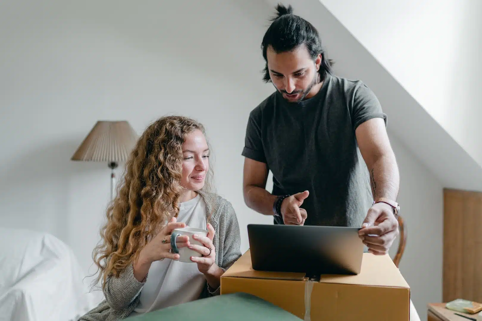 Un couple prépare son projet de construction dans leur chambre avec leur ordinateur portable